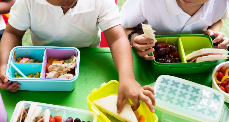 Imagem de crianças em mesa de refeitório se alimentando