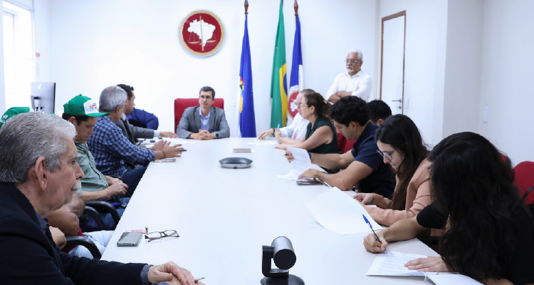 Fotografia dos participantes da reunião sentados em volta da mesa