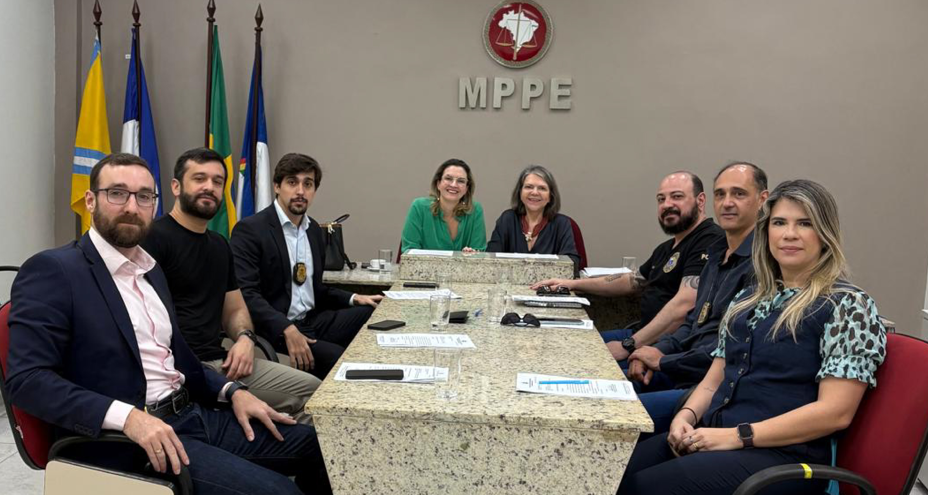 Fotografia de participantes da reunião sentados em volta da mesa de discussões
