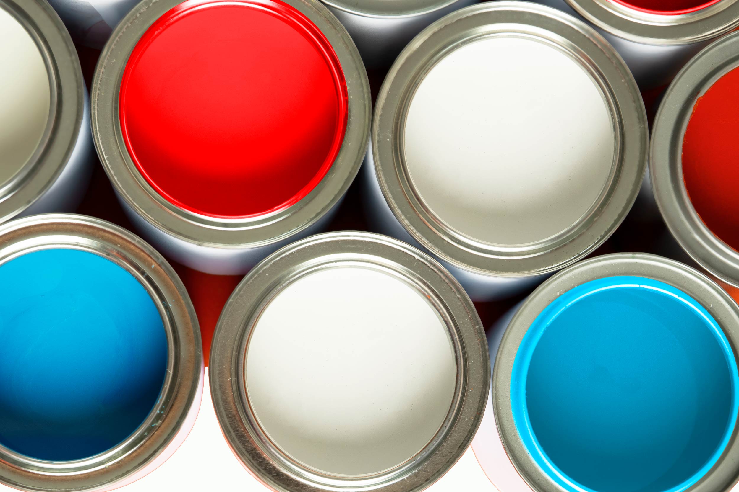 Imagem de cima de latas de tinta nas cores branca, azul e vermelha