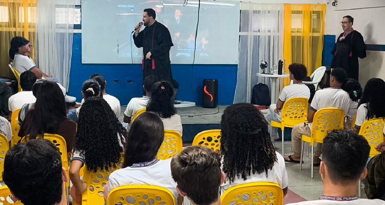 Fotografia de promotores falando para estudantes na escola