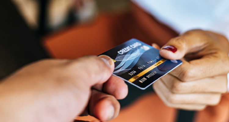 Imagem de pessoa repassando cartão de banco a outra