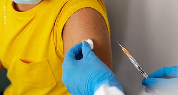 Fotografia de pessoa sendo vacinada por profissional segurando seringa