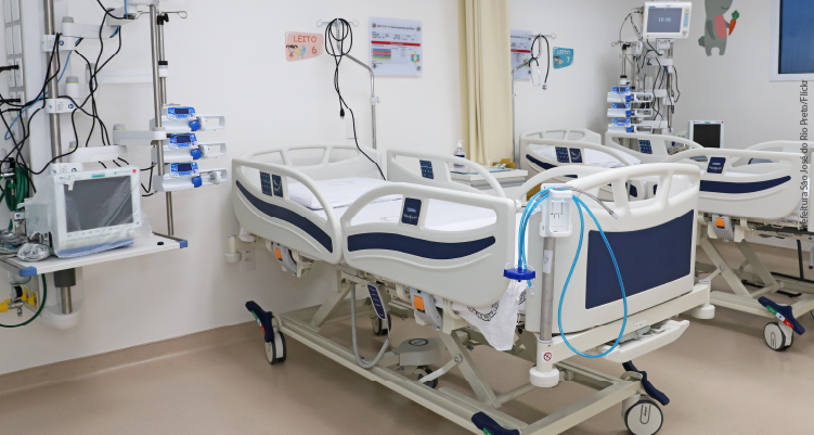 Fotografia de camas de hospital ao lado de equipamentos de UTI