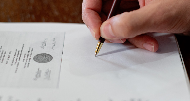 Imagem de pessoa assinando papel 