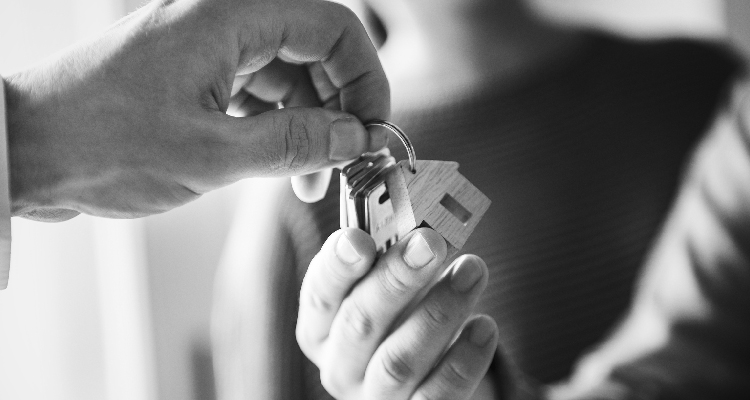 Fotografia em preto e branco de mão de homem entregando chaves a mão de mulher